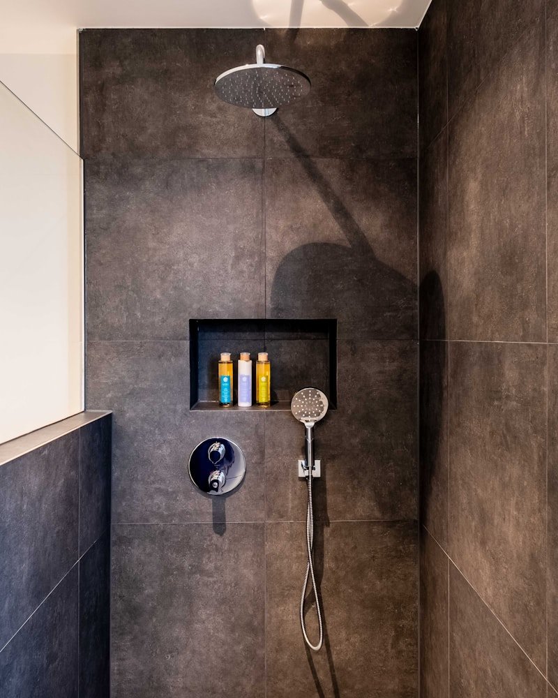 Premium dark-slate shower interior with rain head and integrated niche