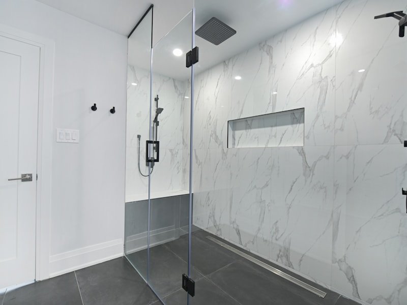 Frameless glass enclosure with matte black hardware and marble walls